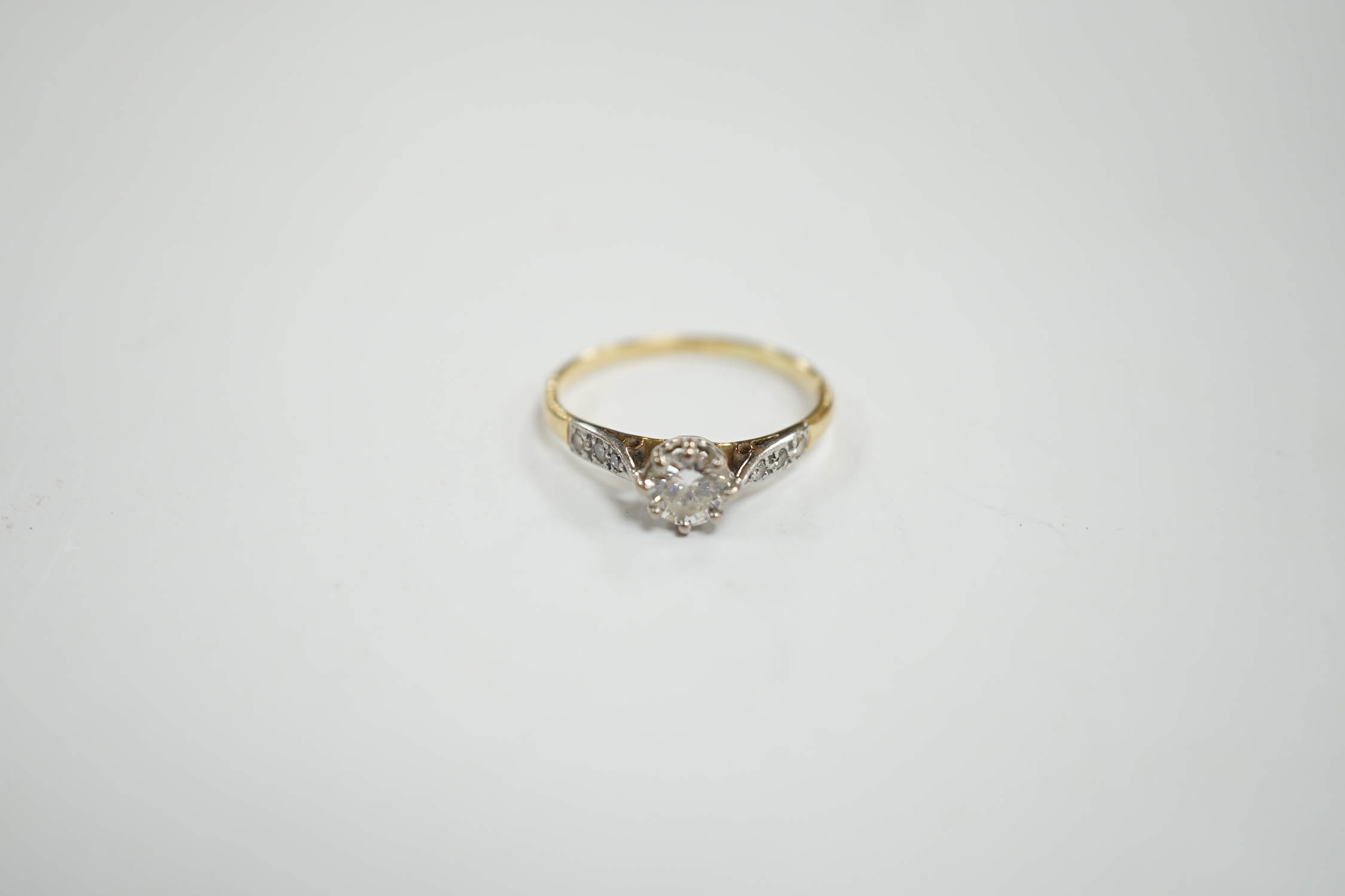 An 18ct and single stone diamond set ring, with diamond chip set shoulders, size M, gross weight 1.9 grams.